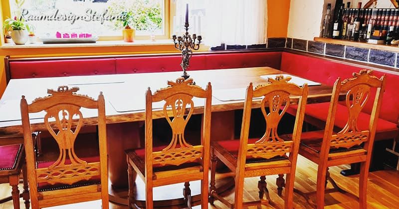 Holzsitzbank mit Tisch und Stühlen mit roter Polsterung von Raumdesign Stefanie